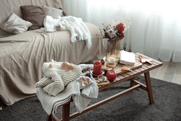 cozy-home-composition-with-candles-book-knitted-sweaters-leaves-min