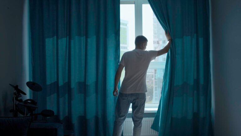 early-morning-man-coming-window-pulling-curtains-apart-media-looking-city_1096515-33915