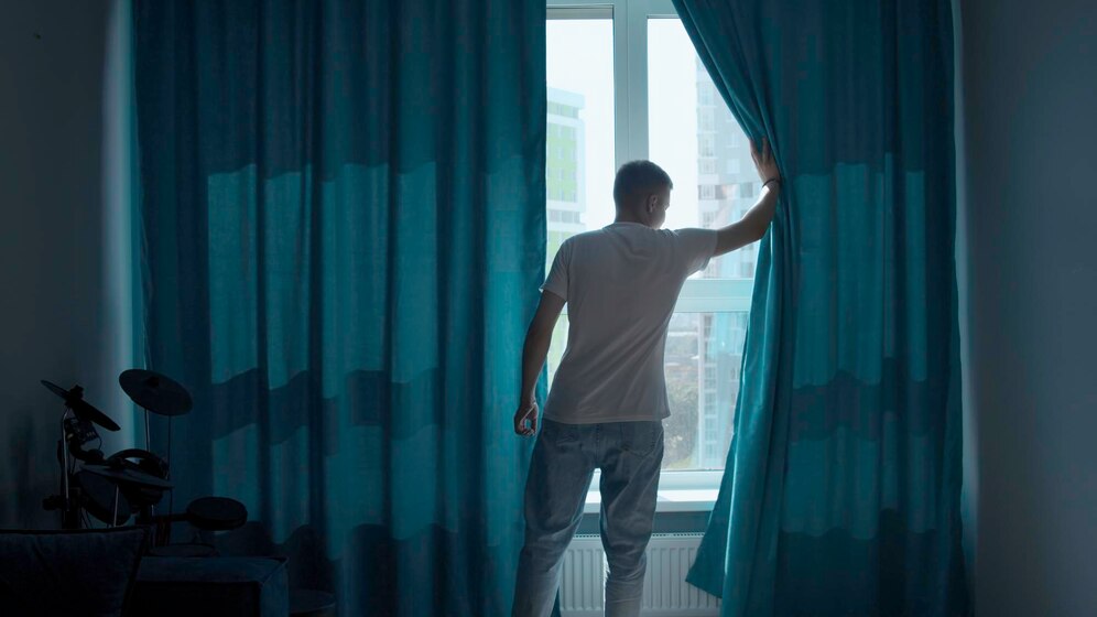 early-morning-man-coming-window-pulling-curtains-apart-media-looking-city_1096515-33915